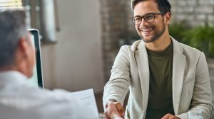 Happy male candidate handshaking with a manager after successful job interview in the office.